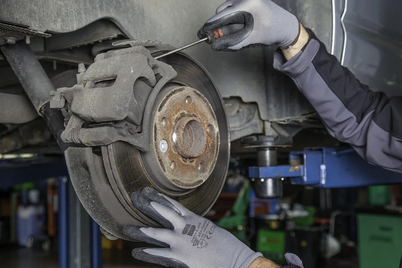 Gloved hands servicing a brake caliper