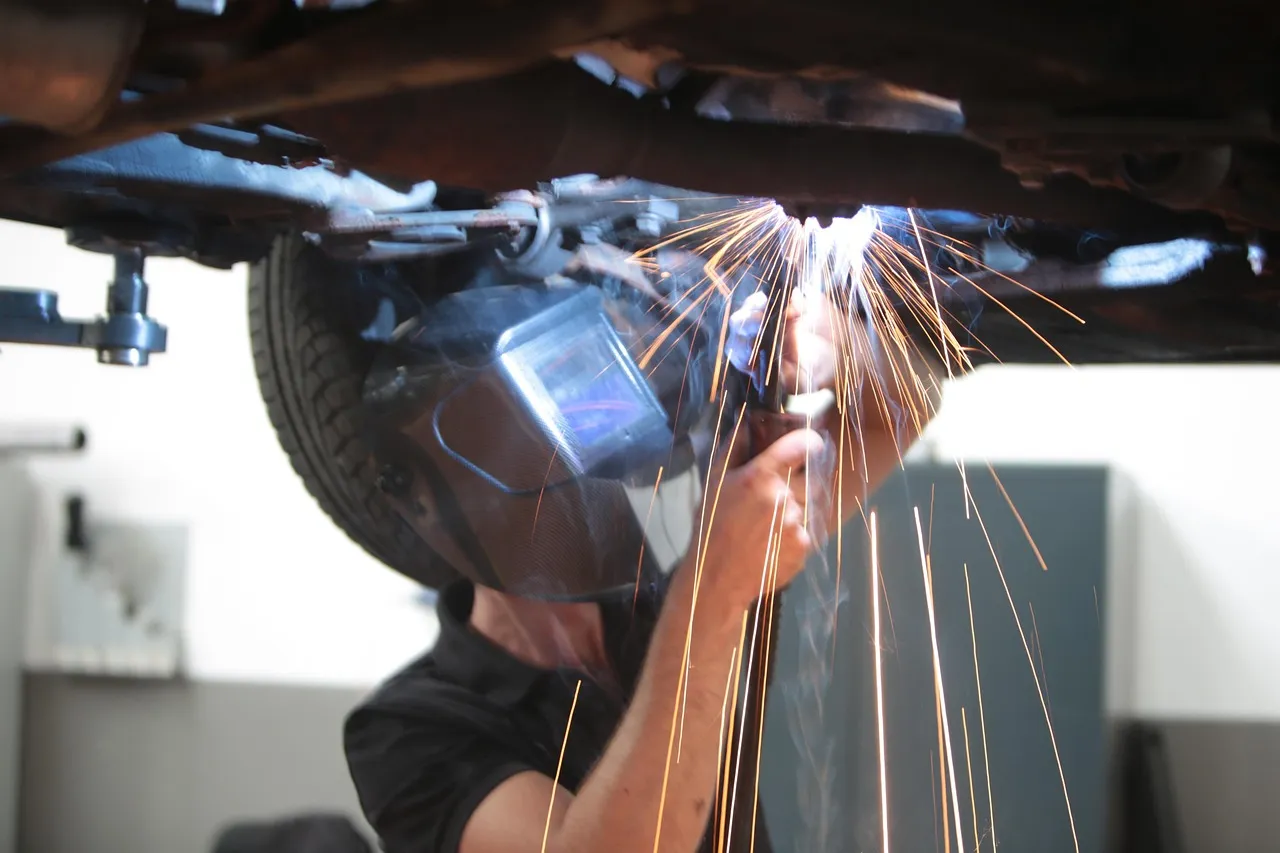 Sparks flying as a technician works on a car headlight assembly